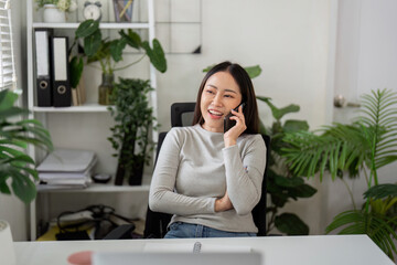 Communication and Connection. A woman happily talks on the phone while working from home.
