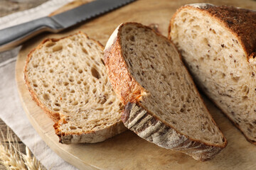 Cut loaf of fresh bread and knife on wooden table, closeup