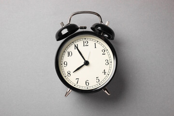 One black alarm clock on light grey background, top view