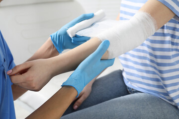 Doctor bandaging patient's elbow in clinic, closeup