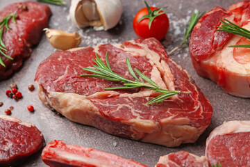 Pieces of raw beef and spices on brown textured table, closeup