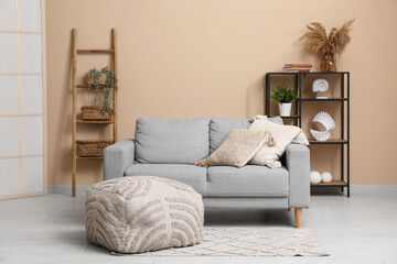 Interior of stylish room with grey sofa, wooden ladder and shelving unit
