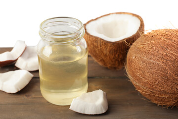 Coconuts and cooking oil on wooden table against white background
