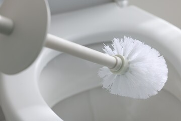 Cleaning toilet bowl with brush indoors, closeup