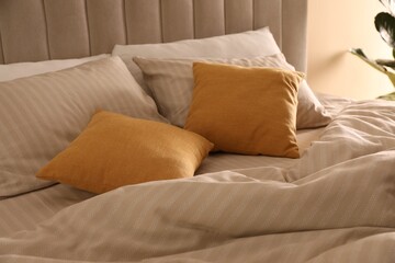 Comfortable bed with soft linens in stylish room, closeup. Interior design