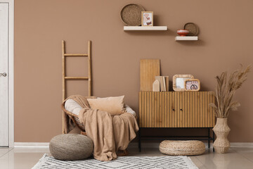 Interior of living room with wicker armchair, ladder and home decor on commode