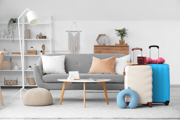 Interior of living room with stylish suitcases, travel pillows and passports