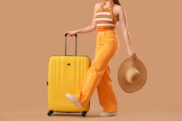 Young woman with suitcase and wicker hat on beige background, closeup. Travel concept
