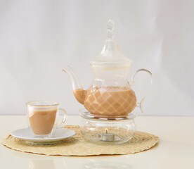 hot milk tea with teapot served in glass cup isolated on background side view of hot drink Karak Tea