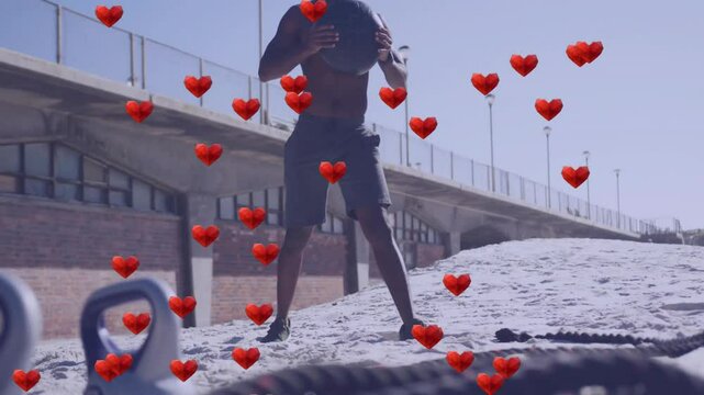 Exercising on beach, man with medicine ball and animation of red hearts
