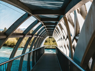 Futuristic glass tunnel architecture casts urban light along a metal pedestrian walkway