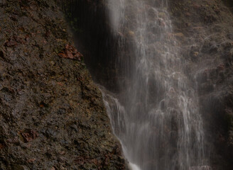 Closeup of a waterfall cascading over a rugged rocky surface in forest