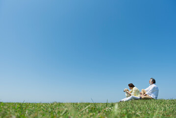 海の見える丘で愛犬と触れ合うシニア夫婦