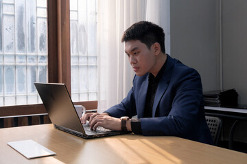 Young businessman focused on laptop in modern office setting during working hours