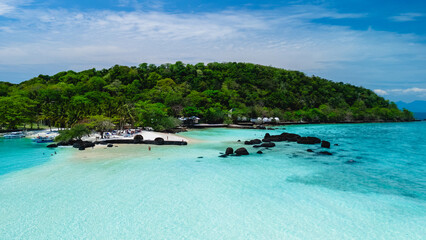 Experience the tranquil allure of Koh Kham Island Thailand, featuring soft sandy beaches and crystal-clear waters. Visitors enjoy leisurely activities amidst lush greenery and rocky formations.