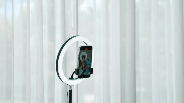 Rear view behide woman influencer shoot live stream vlog video review clothe crucial social media or blog. Girl with apparel studio lighting for marketing recording session broadcasting online