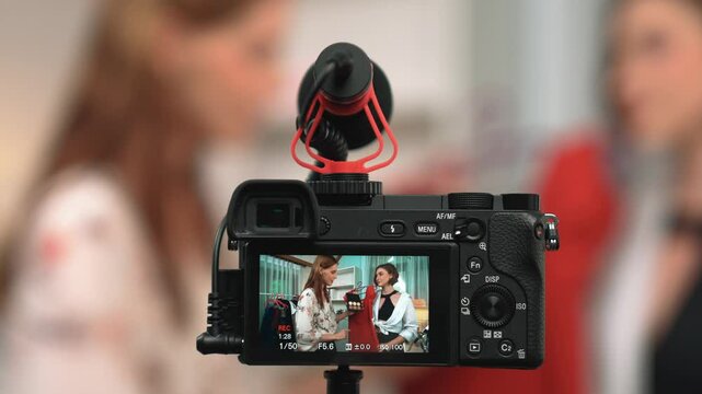 Rear view behide camera screen display two women influencer shoot vlog video review clothes prim social media or blog. Girls with apparel studio lighting for live streaming marketing recording session