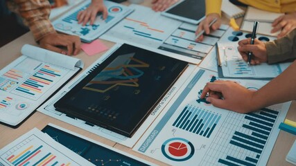 A vibrant office scene featuring diverse professionals engaged in data analysis with digital devices, emphasizing collaboration, strategy, and innovative financial solutions. SACTR - Powered by Adobe