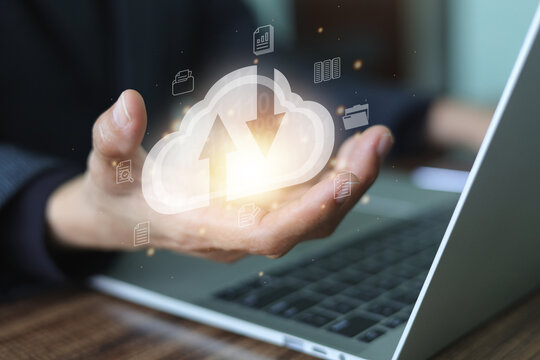 Businessman hand holding with a glowing cloud icon featuring upload and download arrows, and the cloud icon are digital document symbols, cloud computing, data storage, and file transfer technology..