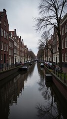 Fototapeta premium Historic Canals in Netherlands Utrecht feature red brick buildings flanking calm water reflecting overcast sky. Concept of tranquility in Historic Canals in Netherlands Utrecht landscape.