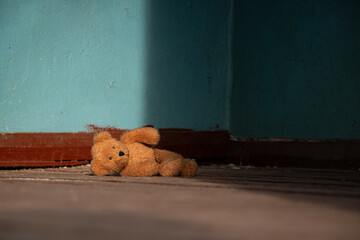 A brown soft teddy bear lies abandoned on the floor in an old abandoned house in Ukraine