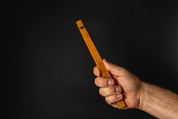 Hand holding a measuring tool against a dark background
