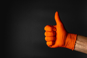 Gloved hand giving a thumbs up against dark background