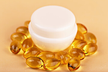 Mockup. Cream jar surrounded by omega vitamin capsules on pastel background. Cream symbolizes vitamin-rich skincare routine. Omega capsules around cosmetic cream highlight beauty skincare care