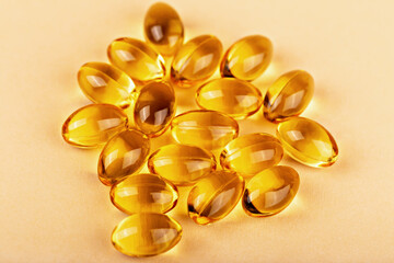 Capsules of vitamin omega supplement on pastel beige background. Vitamin capsules symbolize dietary...