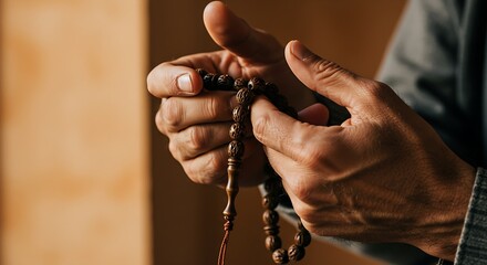 A close-up of a person’s hands holding prayer beads (rosary, mala, or tasbih).