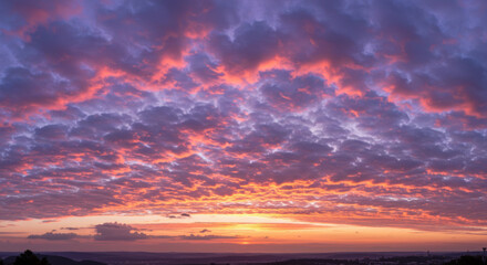 Fototapeta premium A dramatic sunset paints the sky with vibrant colors over a distant cityscape.