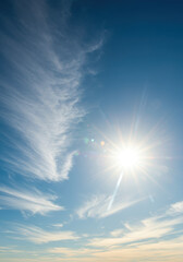 A brilliant sunburst illuminates the blue sky, scattered with delicate cirrus clouds.