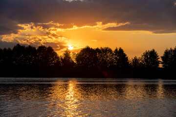 clouds of different colors during sunset on the shore of a lake