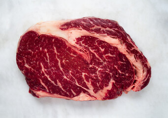 Raw Beef rib eye steak, top view on marble background