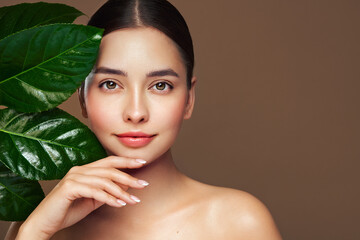Close up woman face with green exotic leaf. Skin care beauty treatments concept. Model with clean,...