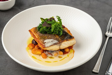 Crispy-skinned pan-seared fish fillet with chickpeas, creamy sauce, and fresh greens