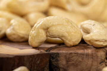 large cashew nuts are scattered on a larch board
