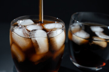 A glass of soda with ice cubes in it. A straw is in the glass