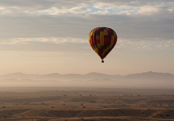 Obraz premium A colorful hot air balloon drifts serenely across a vast desert landscape at sunrise.
