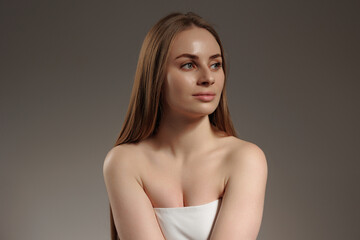 Obraz premium Elegant woman with long hair posing gracefully in soft lighting against a neutral background