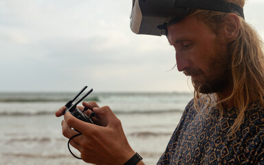 A drone operator wearing a VR headset on a tropical beach in Weligama. Immersed in the virtual...