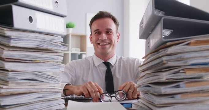 Cheerful businessman in funny glasses, working on documents at desk in the office. Gives a thumbs up, balancing business tasks with a playful attitude while managing accounting tasks.