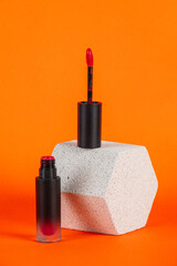 Mockup of black blank thin tube - mascara, lip gloss, gel, eyeliner, oil, etc. Cosmetic package with stylish props on orange background.