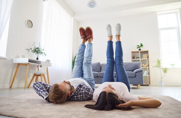 Family couple relaxing at home. Happy young man and woman having a weekend, lying on the floor...