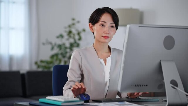 暗いオフィスでパソコンを使ってデータを確認するミドル女性ビジネスパーソン