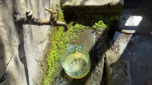 Tanica d'acqua in vetro riempita con acqua di sorgente proveniente da una fontana