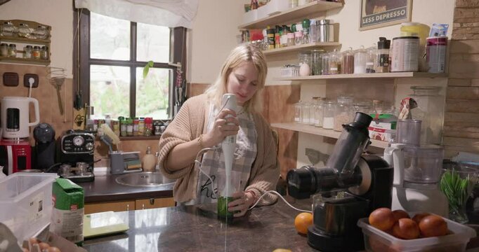 A young woman is blending a wild bear garlic in a kitchen