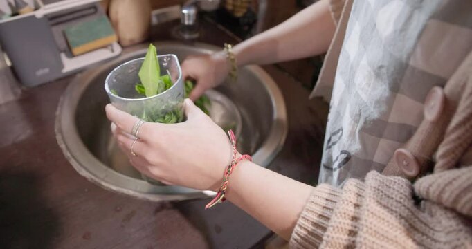 A young woman is blending a wild bear garlic in a kitchen