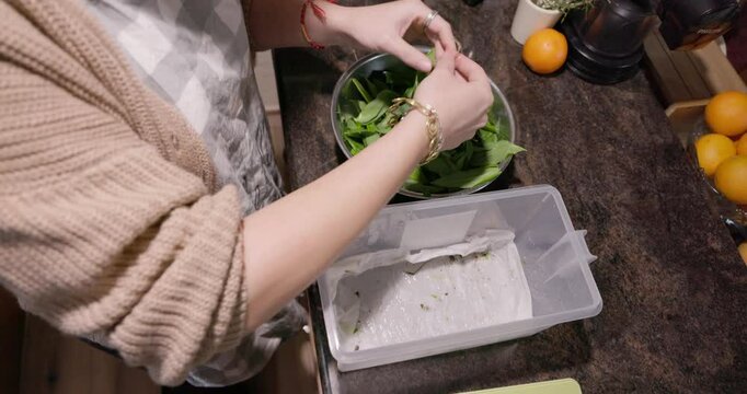 A young woman is blending a wild bear garlic in a kitchen