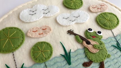 Fototapeta premium Cheerful frog playing guitar amidst embroidered clouds and lily pads.